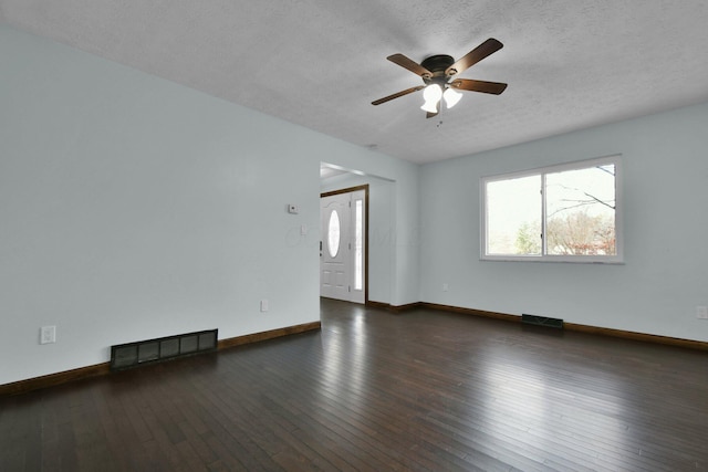 spare room featuring a textured ceiling, ceiling fan, and dark wood-type flooring