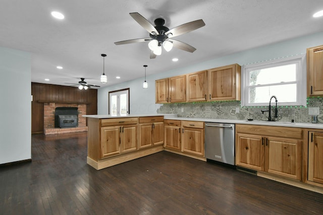 kitchen with kitchen peninsula, a brick fireplace, decorative light fixtures, dishwasher, and dark hardwood / wood-style floors