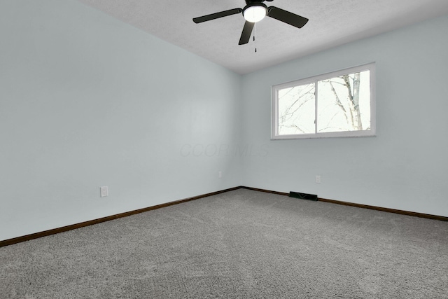 carpeted empty room featuring ceiling fan and a textured ceiling