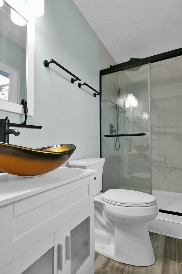 bathroom featuring hardwood / wood-style floors, vanity, a shower with door, and toilet