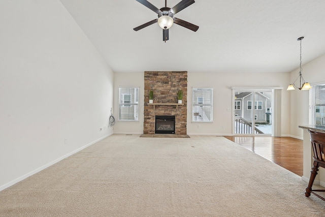 unfurnished living room featuring ceiling fan with notable chandelier, a fireplace, and light carpet