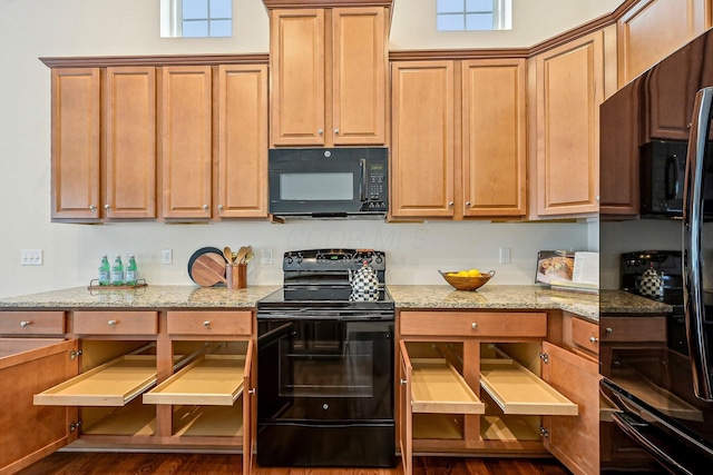 kitchen featuring dark hardwood / wood-style floors, black appliances, and light stone countertops