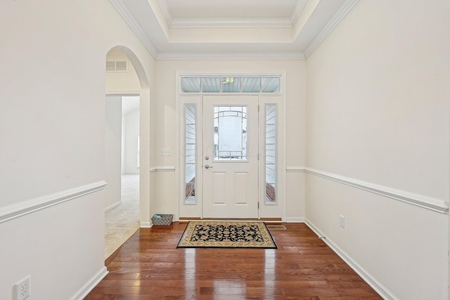 entryway with dark wood-type flooring, a raised ceiling, and ornamental molding