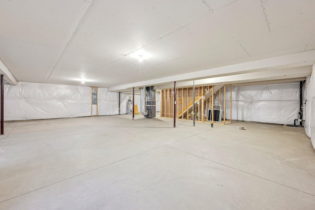 basement featuring electric panel, heating unit, and water heater