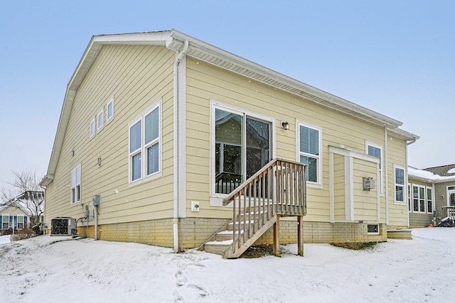 snow covered rear of property with central air condition unit