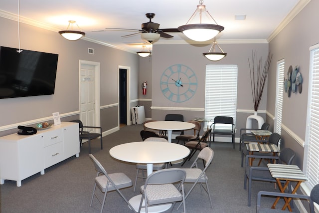 dining room with ceiling fan, ornamental molding, and dark carpet