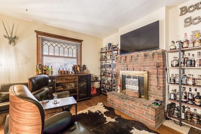 living room featuring bar area, a fireplace, and hardwood / wood-style flooring