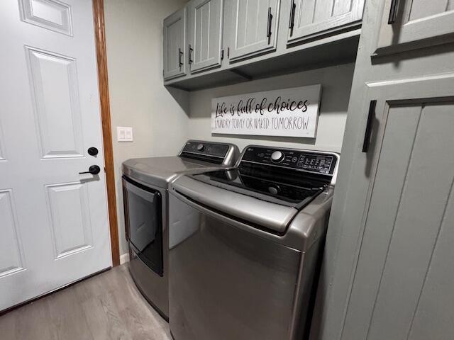 washroom featuring cabinets, independent washer and dryer, and light hardwood / wood-style flooring