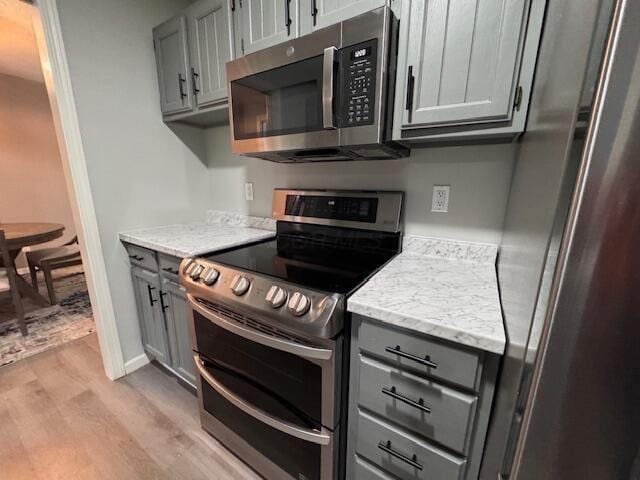 kitchen with gray cabinets, light hardwood / wood-style flooring, and stainless steel appliances