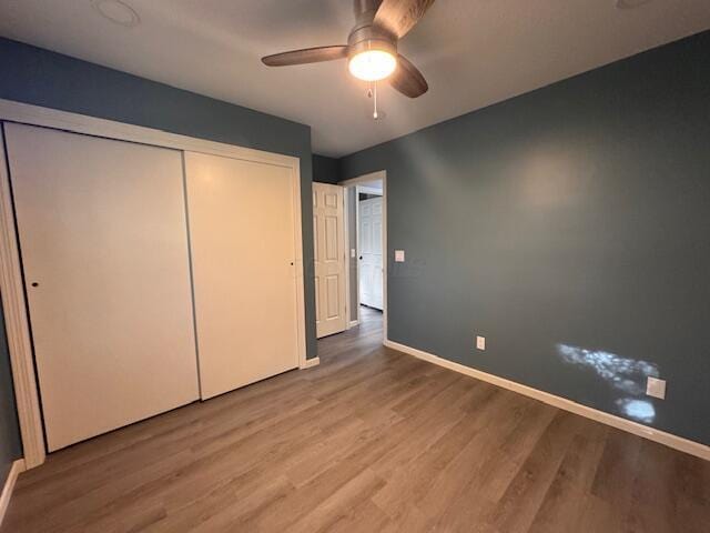 unfurnished bedroom with a closet, hardwood / wood-style flooring, and ceiling fan