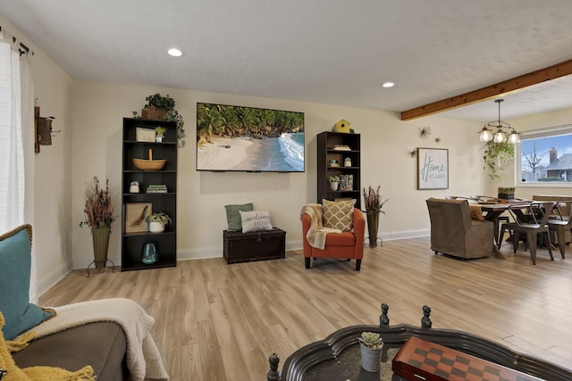 living room featuring a chandelier, beam ceiling, and light wood-type flooring