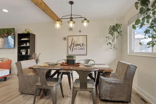 dining room featuring beamed ceiling and light hardwood / wood-style floors