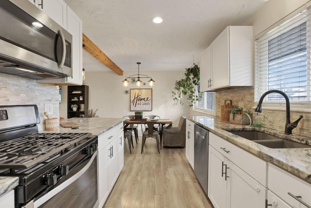 kitchen with sink, beamed ceiling, white cabinets, and appliances with stainless steel finishes