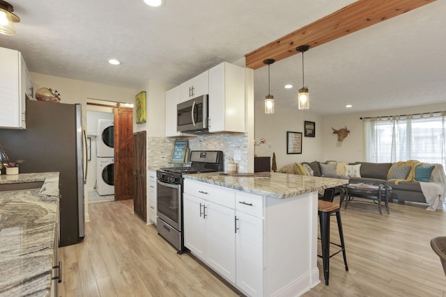 kitchen with a barn door, stacked washer and dryer, white cabinetry, and stainless steel appliances