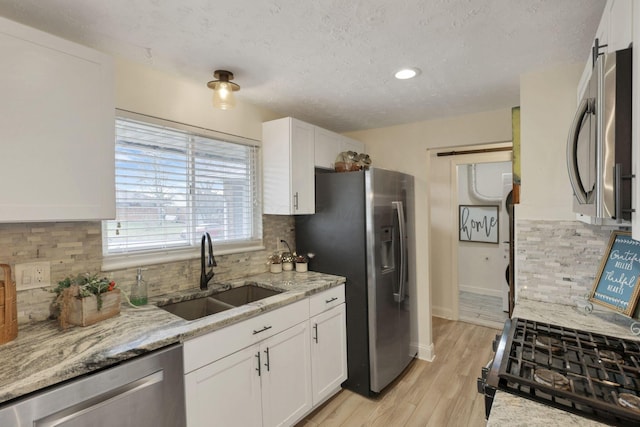 kitchen with decorative backsplash, appliances with stainless steel finishes, white cabinetry, and sink