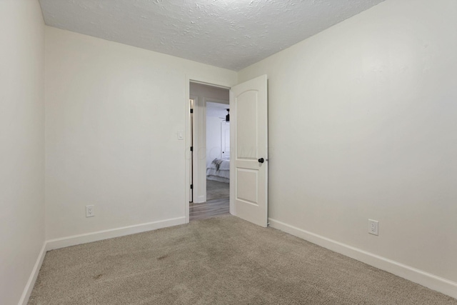 carpeted empty room featuring a textured ceiling