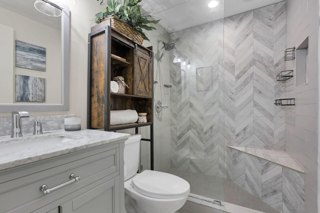 bathroom featuring tiled shower, vanity, and toilet