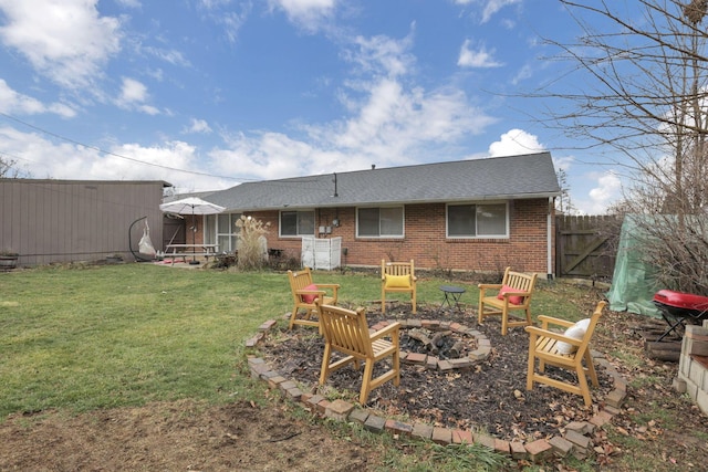 back of property with a fire pit and a lawn