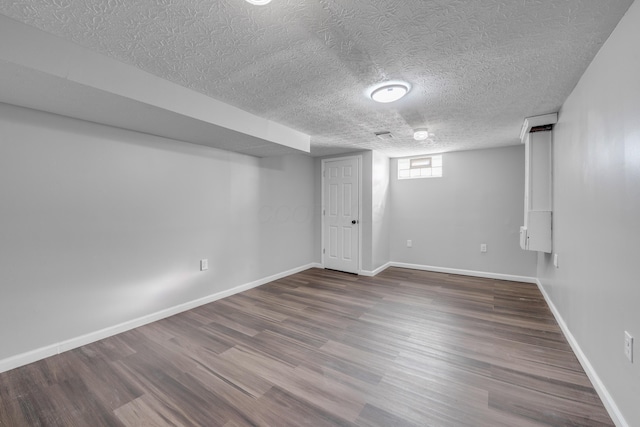 basement featuring wood-type flooring and a textured ceiling