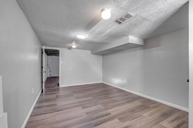 basement with hardwood / wood-style floors and a textured ceiling