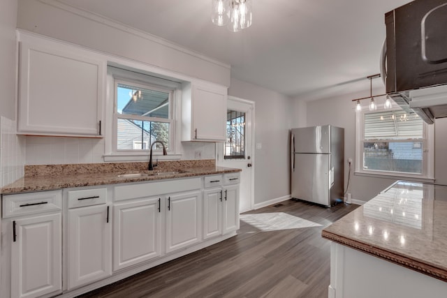 kitchen featuring sink, hanging light fixtures, hardwood / wood-style flooring, white cabinetry, and stainless steel appliances