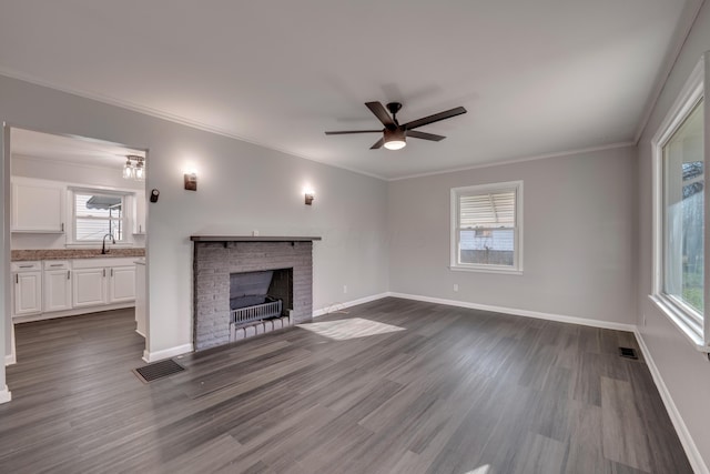 unfurnished living room with dark hardwood / wood-style flooring, ornamental molding, ceiling fan, sink, and a fireplace