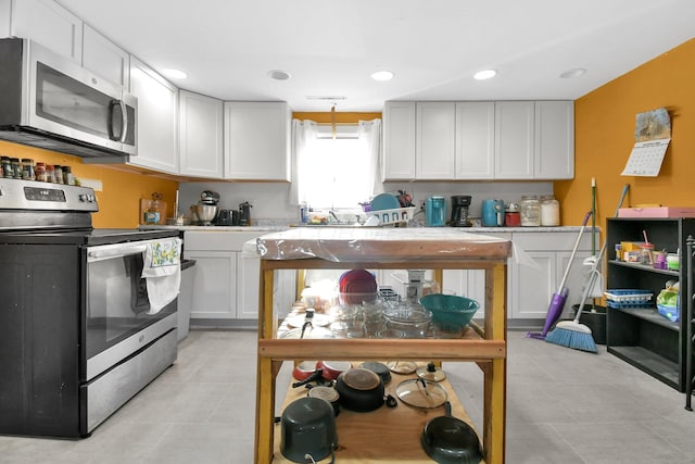 kitchen featuring white cabinets, light tile patterned floors, and appliances with stainless steel finishes