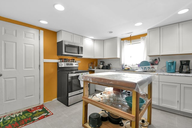 kitchen featuring white cabinetry, stainless steel appliances, and decorative light fixtures