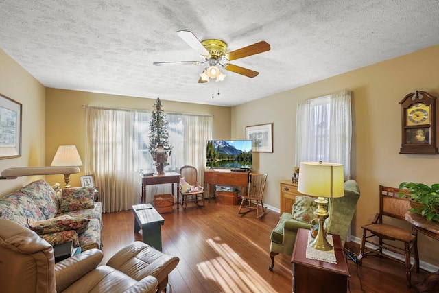 living room featuring wood-type flooring, a textured ceiling, and ceiling fan