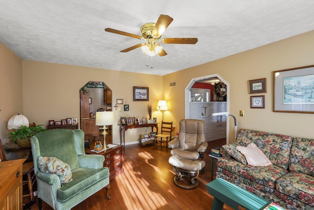 living room featuring a textured ceiling, dark hardwood / wood-style floors, and ceiling fan