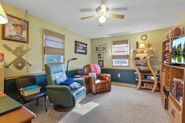 sitting room with ceiling fan, carpet, a healthy amount of sunlight, and a textured ceiling