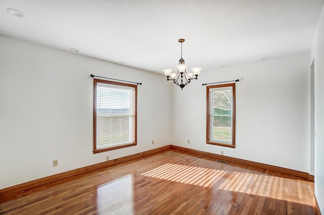 unfurnished room with an inviting chandelier, light hardwood / wood-style flooring, and a healthy amount of sunlight