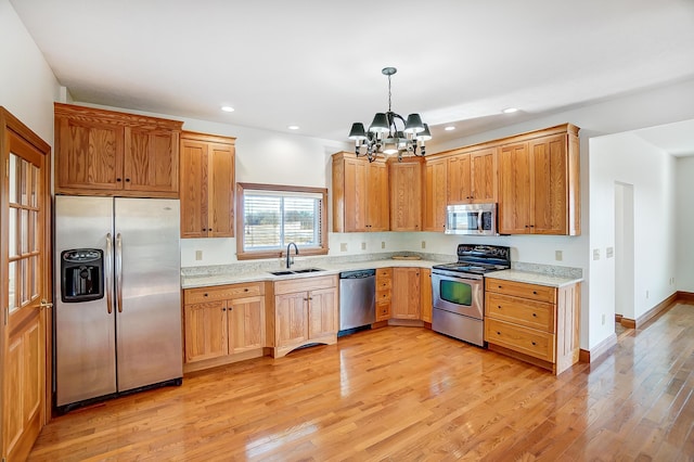 kitchen featuring sink, hanging light fixtures, stainless steel appliances, a chandelier, and light wood-type flooring