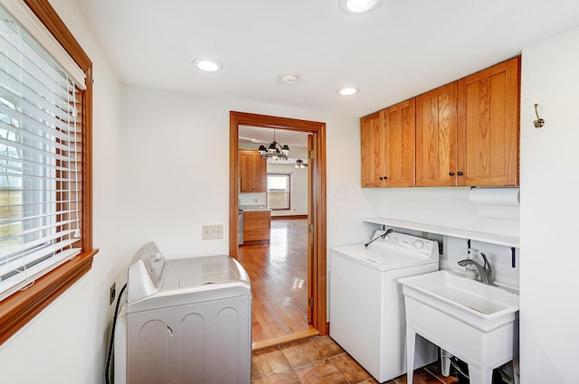 washroom featuring washing machine and dryer, light hardwood / wood-style flooring, cabinets, and sink