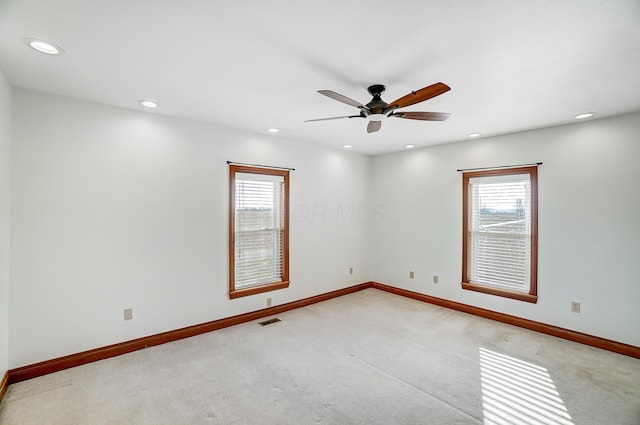 spare room featuring plenty of natural light, ceiling fan, and light carpet