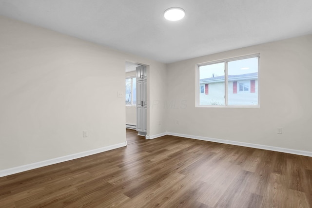 empty room with dark hardwood / wood-style flooring and a wealth of natural light