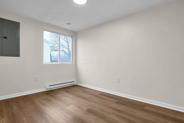 empty room featuring hardwood / wood-style floors, electric panel, and a baseboard radiator