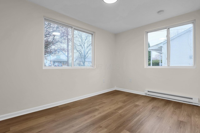 spare room featuring hardwood / wood-style floors and a baseboard heating unit