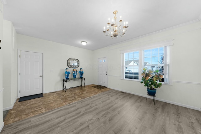 foyer with a chandelier, light wood-type flooring, and ornamental molding