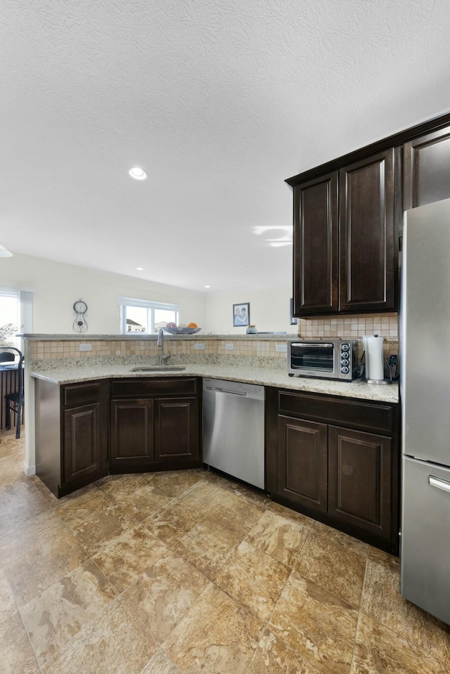 kitchen with decorative backsplash, sink, dark brown cabinets, and appliances with stainless steel finishes