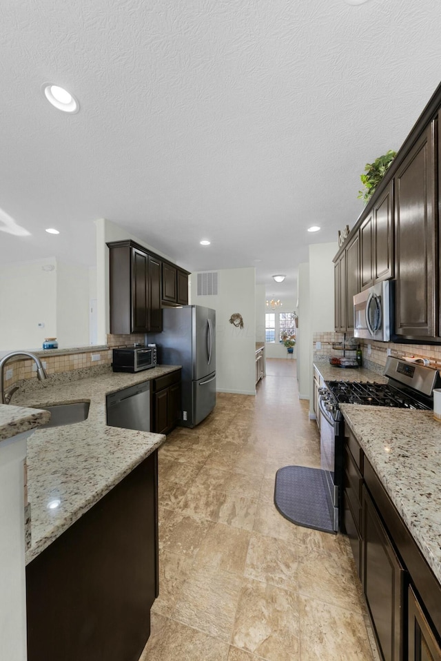 kitchen featuring decorative backsplash, light stone countertops, sink, and appliances with stainless steel finishes