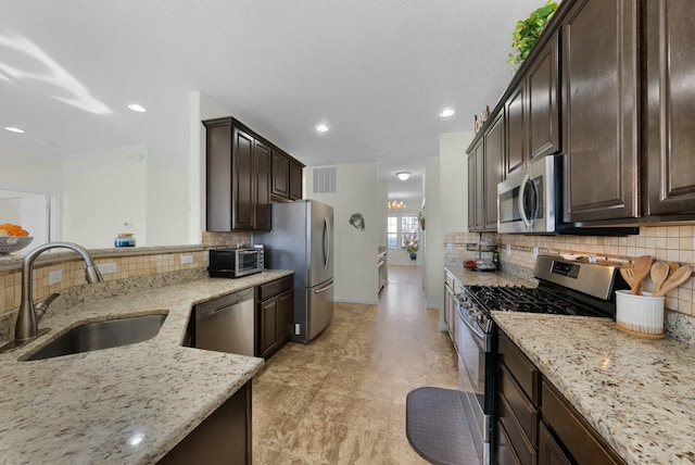 kitchen with light stone countertops, backsplash, stainless steel appliances, and sink