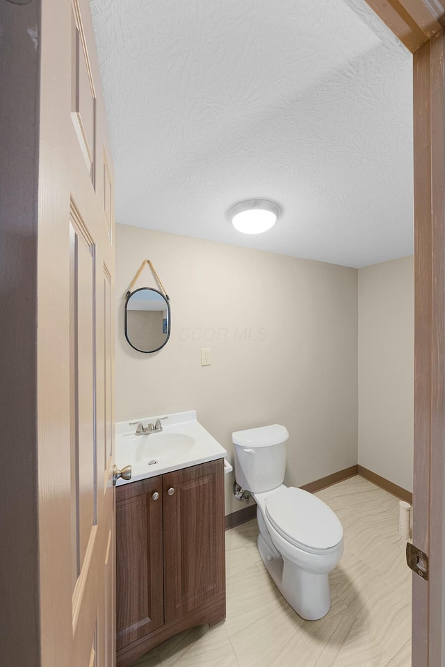 bathroom featuring vanity, a textured ceiling, and toilet