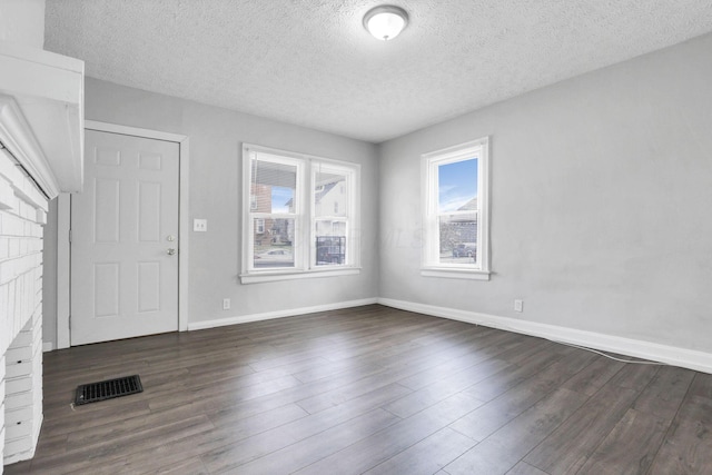 entrance foyer featuring a fireplace, a textured ceiling, and dark wood-type flooring