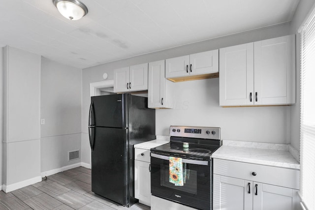 kitchen featuring stainless steel electric range, black fridge, and white cabinetry