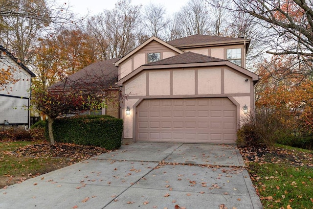 view of front facade featuring a garage, driveway, a shingled roof, and stucco siding