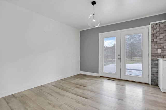 unfurnished dining area featuring light wood-type flooring and french doors