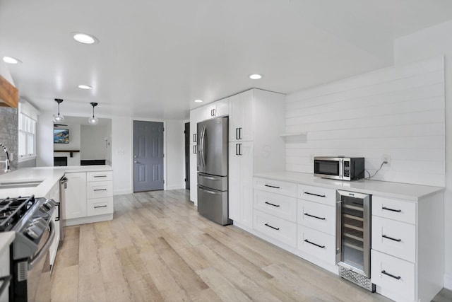 kitchen featuring white cabinets, sink, wine cooler, appliances with stainless steel finishes, and kitchen peninsula