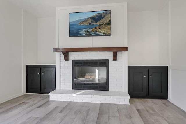 interior details featuring a brick fireplace and hardwood / wood-style flooring