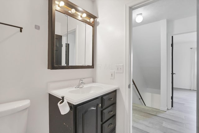 bathroom with a textured ceiling, vanity, and toilet